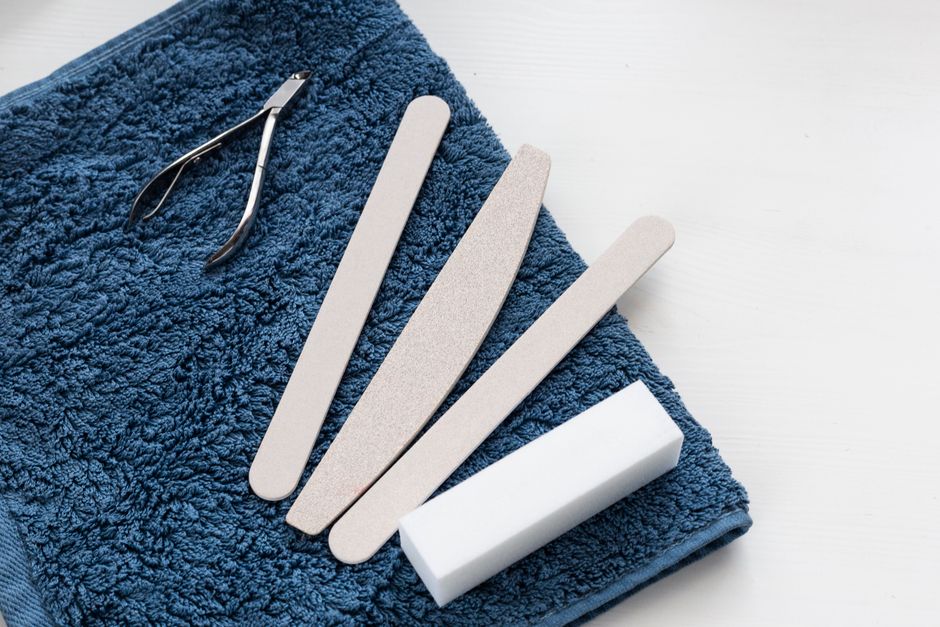 A neatly arranged manicure toolkit with cuticle nipper and nail files on a soft blue towel, ideal for salons.